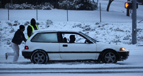 A motorist gets freed after being stuck on a lane barrier in the early morning commute near Interstate 405 in Kirkland, Washington January 18, 2012. Washington braced for epic snowstorm