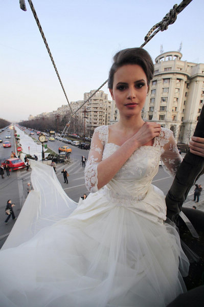 Emma, a 17 year-old model, sits on a hot air balloon as she wears the wedding dress with the longest tail in the world during a Guinness World Record attempt in Bucharest, March 20, 2012. Wedding dress with world's longest tail