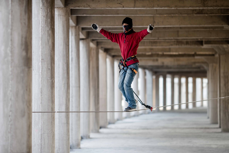 Tightrope walker Zhang Liang walks on a thin rope at an abandoned construction site in Beijing, Jan 26, 2013. Dizzy trend of tightrope walking