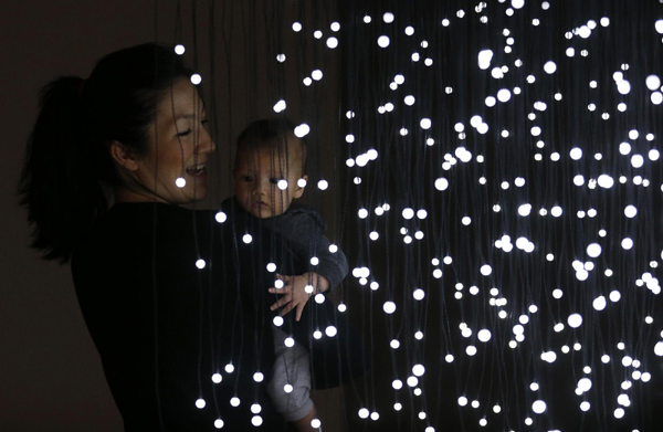 A woman poses for a photograph inside the light installation 'You and I, Horizontal' from 2005 by Anthony McCall at an exhibition entitled 'Light Show' at the Hayward Gallery in London Jan 29, 2013. 'You and I, Horizontal' light show in London