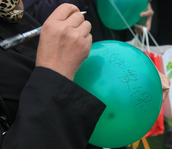 A parent writes a wish on a balloon for her lost child during a ceremony in Shanghai, March 24. Solemn prayers for lost children