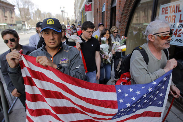 People move items from a vigil after the barricade they were hanging on was taken down and a portion of Boylston Street reopened a day after two explosions near the finish line of the Boston Marathon in Boston, Massachusetts April 16, 2013. Boston mourns bombing victims