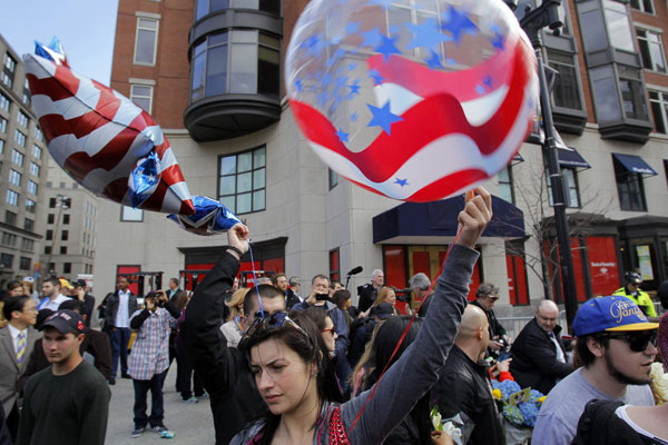People hold patriotic balloons as they stand on a portion of Boylston Street which was reopened a day after two explosions near the finish line of the Boston Marathon, Massachusetts April 16, 2013. Boston mourns bombing victims