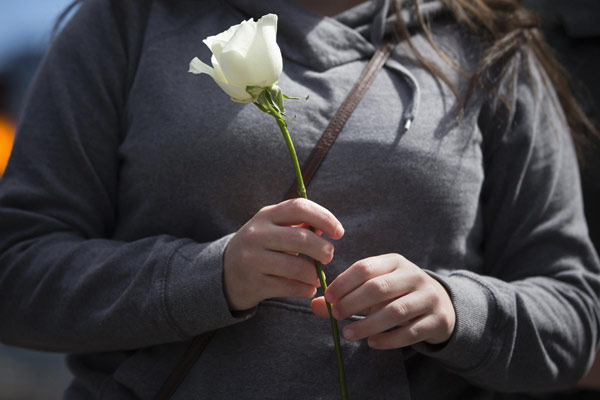 Jackie Pickering holds a flower outside the barricaded entrance at Boylston Street near the finish line of the Boston Marathon in Boston, Massachusetts April 16, 2013. Boston mourns bombing victims