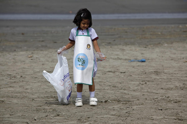 A schoolgirl collects rubbish from Karachi's Clifton beach early morning April 22, 2013, during a cleaning campaign as part of the commemoration of Earth Day. Earth Day marked around the world