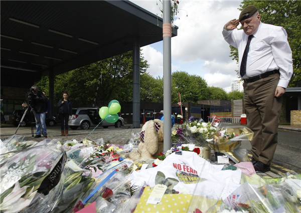 Former soldier Scott Perry salutes over flowers left outside an army barracks near the scene of a killing in Woolwich, southeast London May 23, 2013. In memory of dead London soldier