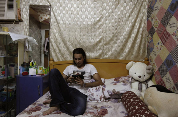Bangladeshi refugee Nazmul Huda, nicknamed Arif, 26, who fled with his friend Delwar, plays an electronic game on his phone in his shack inside a quarters at the rural Ping Chi in Hong Kong's New Territories June 19, 2013. World Refugee Day: home is but a faint dream