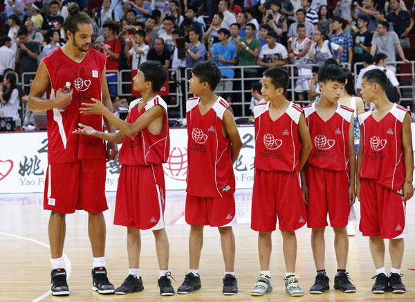 A player from a primary school basketball team offers water to Chicago Bulls center Joakim Noah after a charity basketball match between the NBA All-star team and Chinese National team in Beijing, July 1, 2013. Yao Ming, McGrady team up for charity