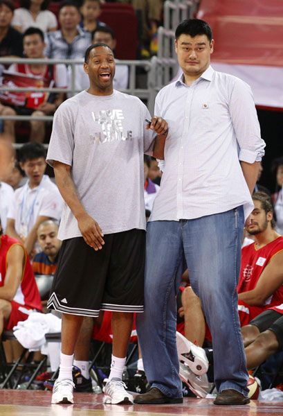 Retired Chinese and NBA basketball star Yao Ming (R) and Tracy Mcgrady react as they watch children's basketball match during the break of a charity basketball match between NBA All-star team and Chinese National team in Beijing, July 1, 2013. Yao Ming, McGrady team up for charity