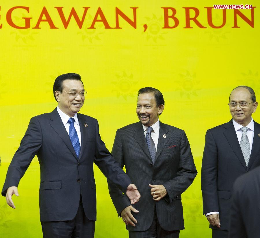 Premier Li Keqiang (L) talks with Brunei's Sultan Hassanal Bolkiah (C) before taking a group photo with other leaders who attend the 8th East Asia Summit (EAS) in Bandar Seri Begawan, Brunei, Oct 10, 2013. Highlights: Premier Li Keqiang at East Asia leaders' meetings