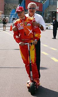 Ferrari's Formula One driver Michael Schumacher of Germany and his manager Willy Weber (R) ride an electric scooter as they arrive for a free practice session for the Monaco Grand Prix in Monte Carlo May 27, 2006.