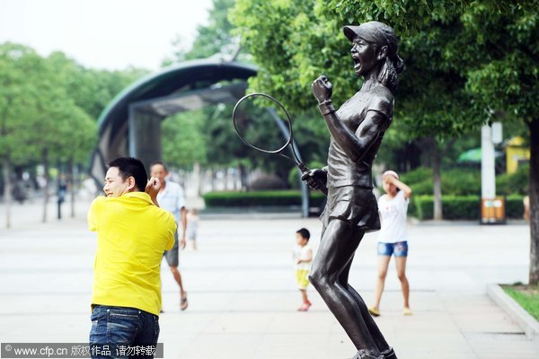 A man poses for a photo in front of a statue of Chinese tennis great Li Na in Wuhan, July 12, 2011. Tennis great immortalized with statue in Wuhan