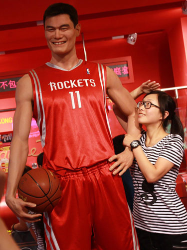 A visitor looks at the statue of Yao Ming at Madame Tussauds Wax Museum in Shanghai, July 20, 2011. Yao Ming, more than a basketball legend