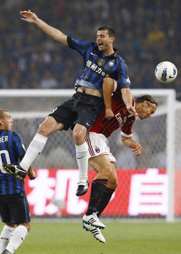 Inter Milan's Thiago Motta (top) jumps for a header with AC Milan's Massimo Ambrosini (R) during their Italian Super Cup soccer match at the National Olympic Stadium, also known as the Bird's Nest, in Beijing, August 6, 2011. Milan edge out Inter in Super Cup