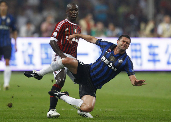 Inter Milan's Thiago Motta (R) falls as he is challenged by AC Milan's Clarence Seedorf during their Italian Super Cup soccer match at the National Olympic Stadium, also known as the Bird's Nest, in Beijing, August 6, 2011. Milan edge out Inter in Super Cup