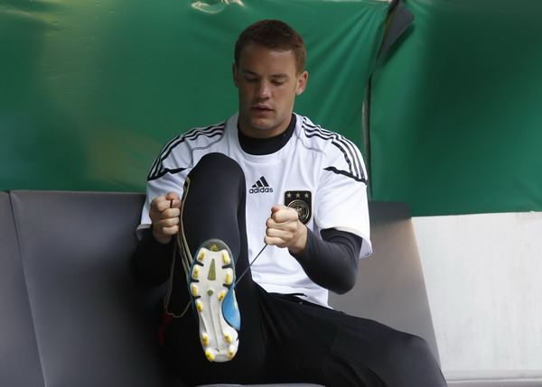 German national soccer player Manuel Neuer puts on his shoes before a training session ahead of their Euro 2012 qualifying match against Austria in Duesseldorf, Aug 31, 2011. Countries warm up for the coming Euro 2012