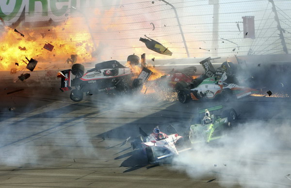 The race car of driver Will Power (L) hits the wall along with drivers J.R. Hildebrand (C) and Charlie Kimball (R) as flames from British driver Dan Wheldon's car burst (at far left) during the IZOD IndyCar World Championship race at the Las Vegas Motor Speedway in Las Vegas, Nevada Oct 16, 2011. Wheldon mourned; search for answers begins