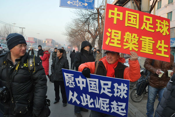 Two soccer fans raise posters that read: 'Rebirth of Chinese soccer' and 'Don't let fans down again' on Monday at the gate of the Tieling Intermediate People's Court where Zhang Jianqiang, former director of the Chinese Football Association's referee committee, stood trial. Provided to China Daily Soccer corruption trials kick off