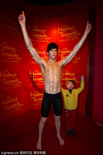 A child, right, poses for a photo with the wax figure of Chinese swimming star Sun Yang at the Madame Tussauds Shanghai wax museum, in Shanghai, Feb 4, 2013. Madame Tussauds Shanghai museum unveils Sun Yang's wax figure