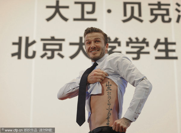 David Beckham shows off his tatoo in Chinese characters at a meeting with students at Peking University in Beijing, on March 24, 2013, as his five-day China visit came to an end. Beckham catches up with Chinese culture on last stop