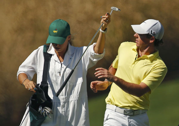 Rory McIlroy of Northern Ireland (R) reacts as his girlfriend, tennis player Caroline Wozniacki of Denmark, gives him a club during the annual Masters Par 3 Contest at the Augusta National Golf Club in Augusta, Georgia, April 10, 2013. Maturing McIlroy calls talk of rivalry with Woods premature