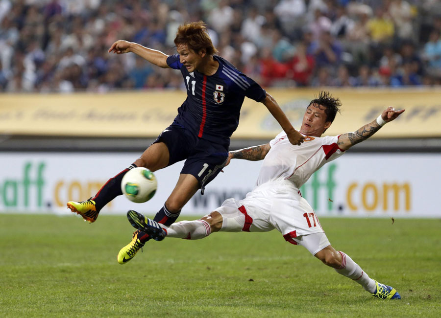 Japan's Genki Haraguchi (L) shoots the ball as China's Zhang Linpeng attempts a tackle during the East Asian Cup soccer championship match at the Seoul World Cup stadium in Seoul, July 21, 2013. Holders China tie Japan 3-3 in East Asian Cup opener