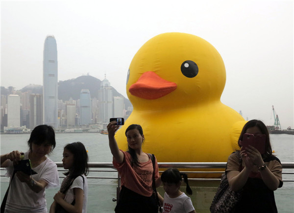 Visitors take photo with 'reviviscent' Rubber Duck floating in Hong Kong's Victoria Harbor, May 22, 2013. Hong Kong hails the return of the duck