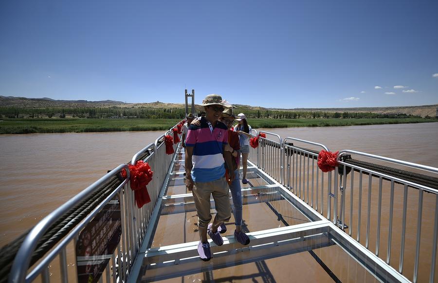 Tourists walk on glass bridge across Yellow River in Ningxia
