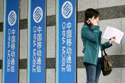 A Chinese woman talks on her mobile phone outside a China Mobile office in Beijing March 17, 2006.