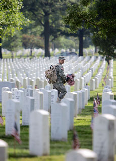 soldier carries flags at Arlington National Cemetery in Arlington, Virginia, May 25, 2006. A flag is placed in front of each of the graves for Memorial Day at the cemetery to commemorate U.S. service men.
