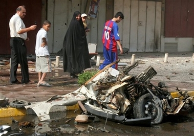 Iraqis walk past a car bomb wreck in Baghdad, Iraq, Wednesday Oct. 18, 2006.