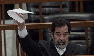 Saddam Hussein, holds up a piece of paper for the judge in court Monday Dec. 4, 2006 during his trial with other defendants in Baghdad, Iraq, for genocide in the 'Anfal' offensive against the Kurds. Saddam and six co-defendants, face possible execution if convicted for the 1987-88 military offensive against the Kurds of northern Iraq. The prosecution estimates that 180,000 Kurds were killed in the campaign, code-named Operation Anfal, in which Saddam's army allegedly destroyed hundreds of villages and killed or scattered their inhabitants. (AP