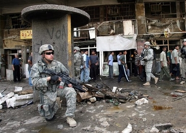 Iraqis and U.S. soldiers survey the scene following a car bomb attack in Baghdad, Iraq, Sunday, May 13, 2007. A parked car bomb exploded near a market in central Baghdad, killing at least 12 Iraqis, wounding 43 and damaging shops, police said. (AP