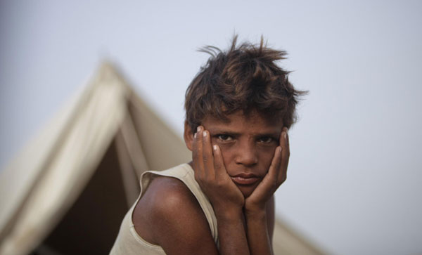 Shafan, 9, displaced by heavy floods for almost a year, is photographed as he sits in front of his family tent while taking refuge along a road in Sukkur, located in Pakistan's Sindh province July 13, 2011. Flood victims in Sukkur, Pakistan