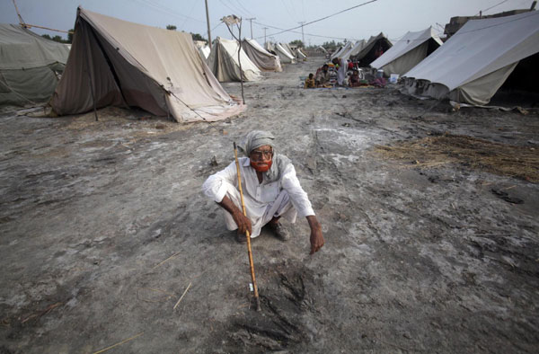 Ganj Bux, 80, displaced by heavy floods for almost a year, sits on the ground in a camp for flood victims in Sukkur, located in Pakistan's Sindh province July 11, 2011. Flood victims in Sukkur, Pakistan