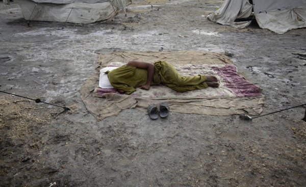 A man, displaced by heavy floods for almost a year, sleeps between tents at a camp along a road in Sukkur, located in Pakistan's Sindh province July 11, 2011. Flood victims in Sukkur, Pakistan