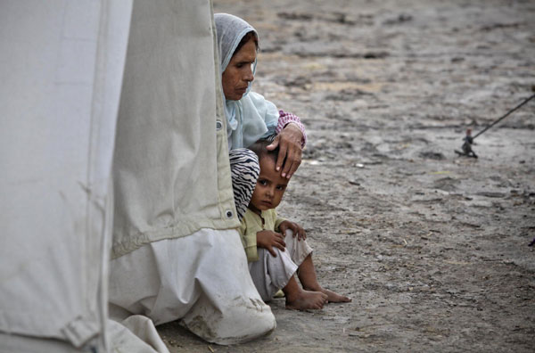 A mother and her child, displaced by heavy floods for almost a year, sit outside their tent while taking refuge in a camp in Sukkur, located in Pakistan's Sindh province on July 11, 2011. Flood victims in Sukkur, Pakistan