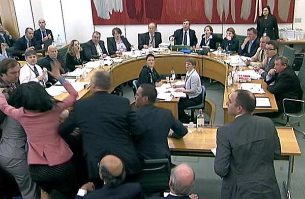 Wendi Deng (2nd L) lunges towards a man trying to attack her husband, News Corp Chief Executive and Chairman Rupert Murdoch, during a parliamentary committee hearing on phone hacking at Portcullis House in London July 19, 2011. Murdoch defends record, attacked by protester