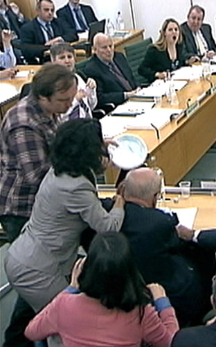 A man (L) tries to attack News Corp Chief Executive and Chairman Rupert Murdoch (R) with a white substance during a parliamentary committee hearing on phone hacking at Portcullis House in London July 19, 2011. Murdoch defends record, attacked by protester