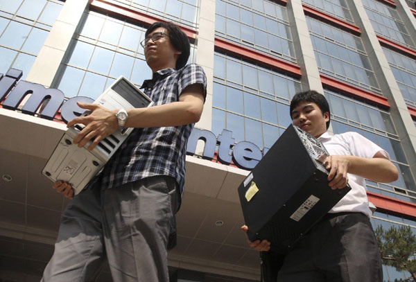 Office workers carry their computers as they evacuate TechnoMart mall in eastern Seoul July 5, 2011. Gym jumping blamed for shaking building