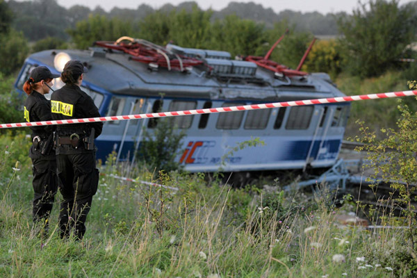 Police personnel stand next to the wreckage of a passenger train that derailed near the village of Baby, in central Poland Aug 12, 2011. Polish train derails, 4 people killed