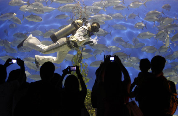 Visitors take pictures of a professional diver wearing an Elvis Presley attire as he swims at an aquarium inside the Ocean Park in Manila August 15, 2011. Presley, the 'King of Rock and Roll', died at his home, Graceland Mansion, in Memphis, Tennessee, at the age of 42 on August 16, 1977 from drug overdose. Fans remember Elvis Presley