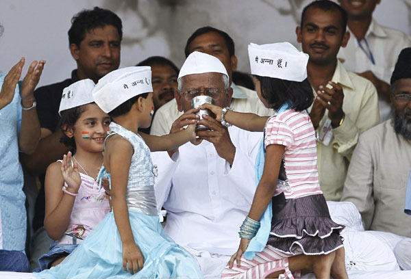 Children Simran (2nd L) and Ikra wearing traditional Indian caps bearing the words: 'I am Anna', offer coconut water and honey to veteran Indian social activist Anna Hazare (C) after he ended his fast at Ramlila grounds in New Delhi August 28, 2011. Indian campaigner finishes fast