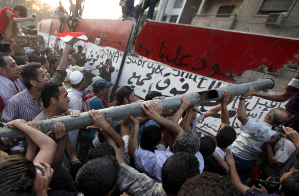 Protesters knock down a concrete wall built in front of the Israeli embassy in Cairo Sept 9, 2011. Egyptian activists on Friday tore down a wall, built around a building housing the embassy in Cairo to protect it from demonstrators, witnesses said. Israeli envoy leaves after Cairo embassy attack