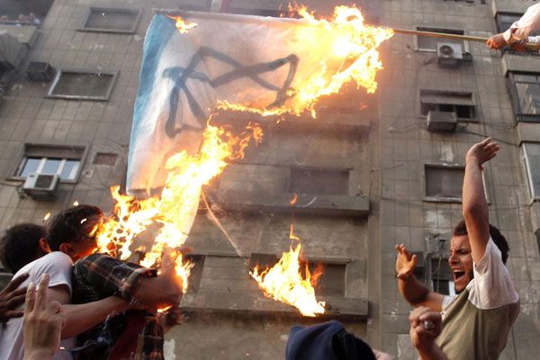 Protesters burn an Israeli flag during a protest in front of the Israeli embassy, as they dismantle a concrete wall built in front of the embassy, in Cairo Sept 9, 2011. Egyptian activists on Friday tore down a wall, built around a building housing the Israeli embassy in Cairo to protect it against demonstrators, witnesses said. Israeli envoy leaves after Cairo embassy attack