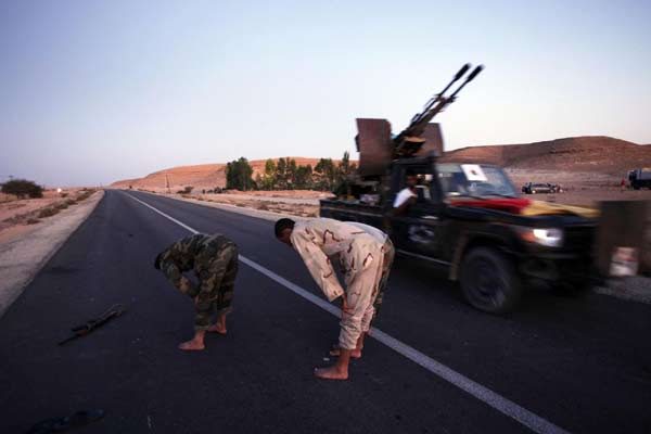 Anti-Gaddafi fighters pray near the north of the besieged city of Bani Walid September 12, 2011. Latest developments in the Libyan conflict