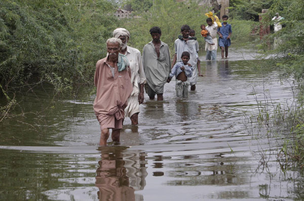 Villagers wade through a flooded street in Pangrio town in the Badin district of Pakistan's Sindh province Sept 14, 2011. 300,000 homeless due to flood in Pakistan