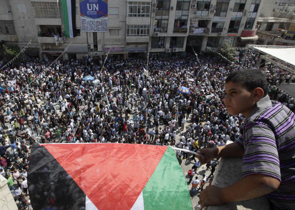 A Palestinian boy holds a flag as he watches a rally in the West Bank city of Ramallah in support of Palestinian President Mahmoud Abbas' bid for statehood recognition in the United Nations, September 21, 2011. Palestinians rally for Abbas's UN statehood bid