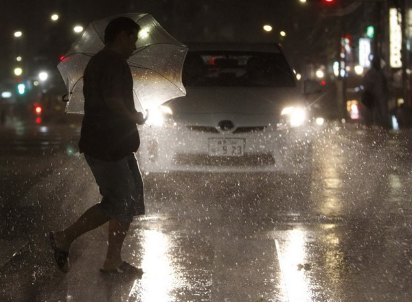 A passer-by struggles with strong winds and rain caused by typhoon Roke as he crosses a road in Tokyo Sept 21, 2011. Typhoon kills 6 in Japan, nuke plant not affected