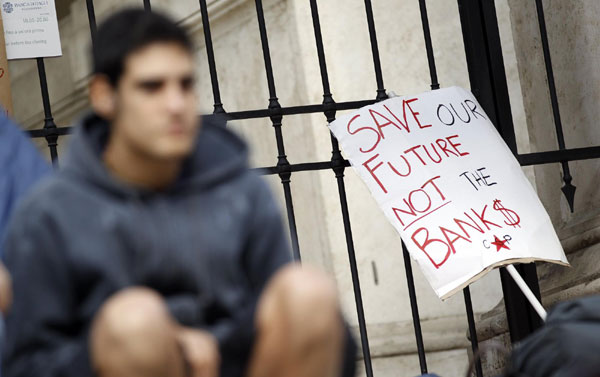 A protester sits near a placard in downtown Rome Oct 14, 2011. Berlusconi wins confidence vote but still weak